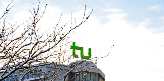 Gebäue der TU Dortmund im Winter Ein Gebäude mit TU Dortmund Logo und mit Schnee bedeckte Äste.
